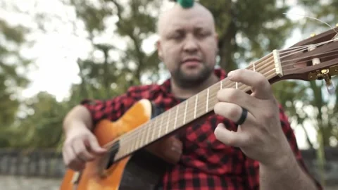 Slow motion of A man with a green mohawk playing guitar at park Stock-Footage 139294927