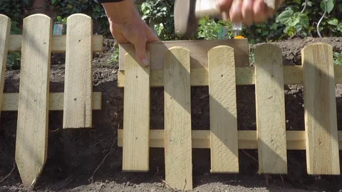 Slow motion: Man hammering a small fence panel into the ground. Stock Footage 89867534