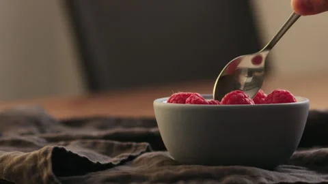 Slow motion man hand eat yougurt with raspberries from a blue bowl on linen Stock Footage 325034803
