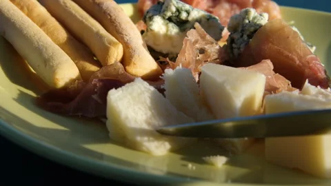 Slow motion man hand salami on olive board next to grissini with prosciutto and Stock Footage 317725280