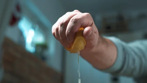 Slow motion of man hand squeezes juice from a lemon in the kitchen at home Stock Footage 129107161