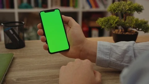 Slow motion man hand uses holding mobile phone with vertical green screen table Stock Footage 117959773