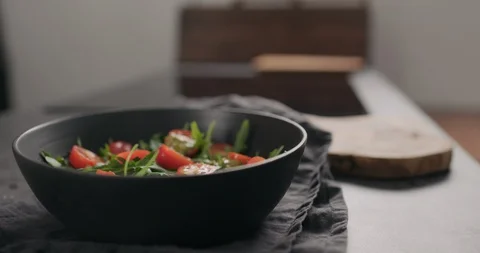 Slow motion man hands hard cheese on cherry tomatoes and fresh arugula in black Stock Footage 128673387