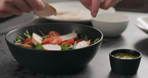 Slow motion man hands put chicken fillet over cherry tomatoes and fresh arugula Stock Footage 128647273