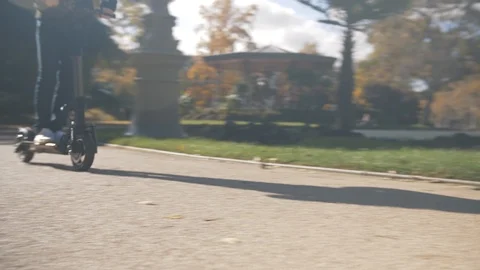 Slow Motion of Man with Helmet Using Electric Scooter in Park with Fountain 2 Vidéo 98757174