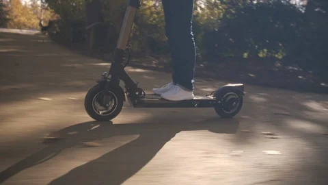 Slow Motion of Man with Helmet Using Electric Scooter in Sunny Park 1 Vidéo 98757418