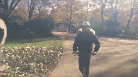 Slow Motion of Man with Helmet Using Electric Scooter in Sunny Park 2 Vidéo 98757451
