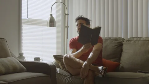 Slow motion of man holding a book as he looks up thinking Stock Footage 114644569