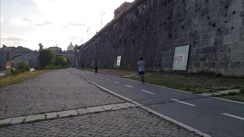 Slow Motion A man jogs In Rome near the Tiber river with view of St. Peter dome Stock Footage 108502898