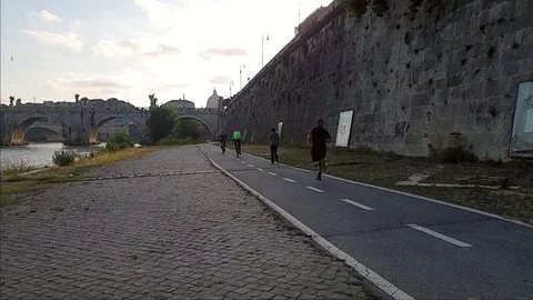 Slow Motion A man jogs In Rome near the Tiber river with view of St. Peter dome Stock Footage 108503078