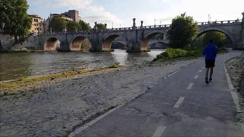 Slow Motion A man jogs In Rome near the Tiber river with Sant'Angelo bridge Stock Footage 108503091