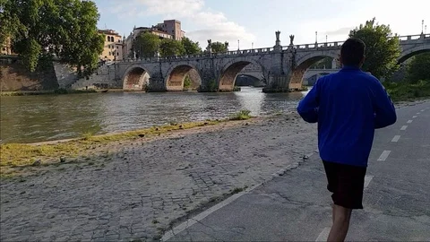 Slow Motion A man jogs In Rome near the Tiber river with Sant'Angelo bridge Stock Footage 108503099