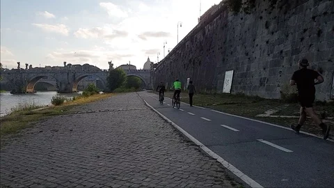 Slow Motion A man jogs In Rome near the Tiber river with view of St. Peter dome Stock Footage 108503418