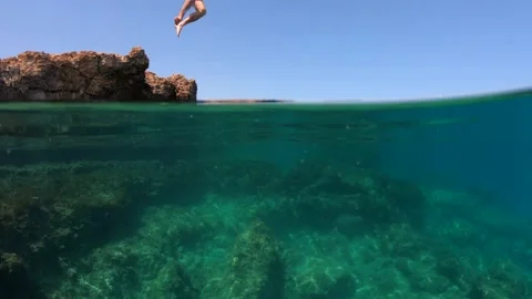 Slow motion of man jumping off cliff into the sea. Underwater Video stock 211179046