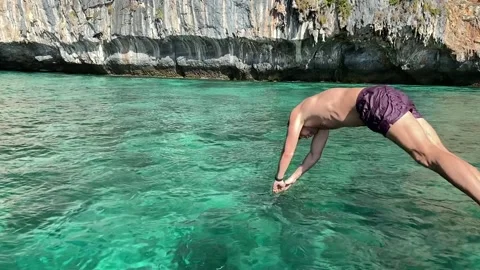 Slow motion of a man jumping into deep turquoise water Video stock 219857267