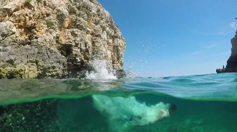 SLOW MOTION: Man jumping head first into refreshing ocean and swims underwater Stock Footage 65579610