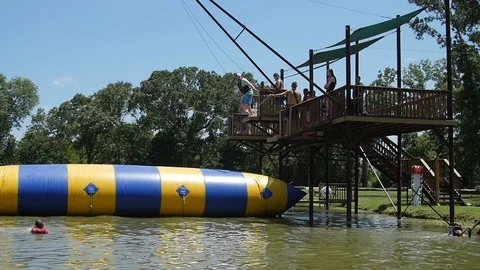 Slow-motion of man jumping on inflatable in lake Stock-Footage 118724417