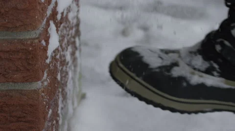 Slow motion man kicking snow off of his winter boots Stock Footage 60412100