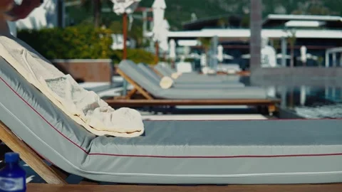 Slow motion of a man laying out a rolled up beige towels on a sun lounger Stock Footage 220208726