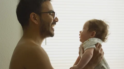 Slow motion of man lifting his baby daughter up at home Stock Footage 114104621