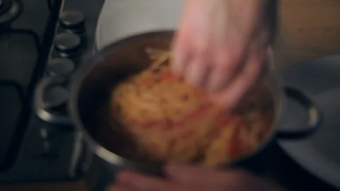 Slow motion a man mixing bolognese tomato sauce into a steaming pan of spaghetti Stock Footage 90833588