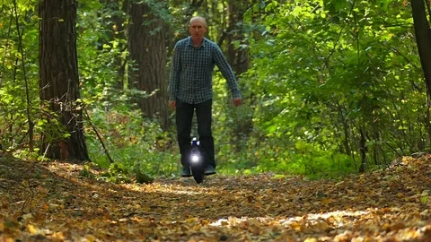  Slow motion. Man on mono wheel with lamp in wood, electrical transport team Stock-Footage 84217664