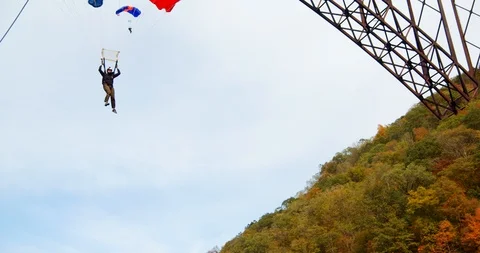 Slow Motion Man with Parachute, Base Jumping Off Bridge in Forest Video stock 127468484