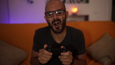 Slow Motion: man plays a video game on the sofa and loose the match. Looser sign Stock Footage 136536281