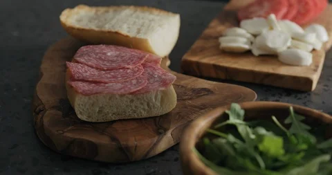 Slow motion man put tomato on ciabatta slice on olive board Video stock 119873651