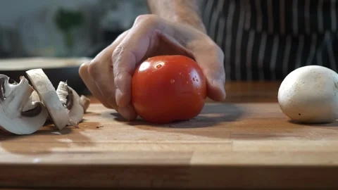 Slow motion. A man puts a tomato next to sliced and whole mushrooms. Culinary Stock Footage 259149272