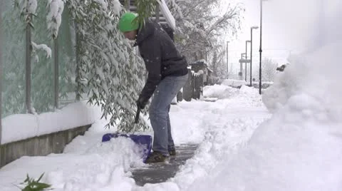 SLOW MOTION: Man removing snow from a sidewalk Stock Footage 22046857
