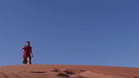 Slow motion of man running and jumping down the face of a sand dune Stock Footage 64710862