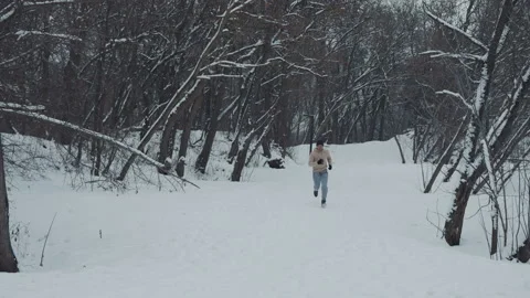 Slow motion man running up the hill in winter forest Stock Footage 148313815