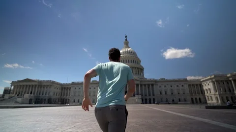 Slow motion of man running towards the US Capitol and turning to show the Stock Footage 128717720