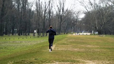 Slow Motion Man Running in Winter Park - Athlete in Black Sportswear Stock Footage 330489837