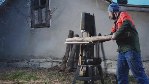 Slow motion of a man sawing a log in the yard of an old house. Family business Stock Footage 276659715