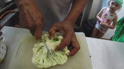 Slow motion of man slicing cauliflower with little girl in background. Stock Footage 42023210