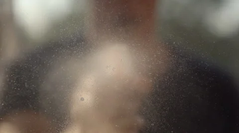 SLOW MOTION: Man sprays soap solution on a window (defocused) Vídeos de archivo 68487445