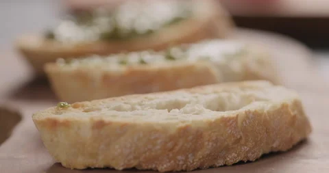 Slow motion man spread pesto on ciabatta slice on olive board Video stock 132034758