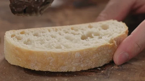Slow motion man spreading chocolate butter on ciabatta slice on olive board Video stock 129074742