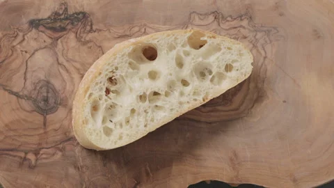 Slow motion man spreading chocolate spread on ciabatta slice on olive board top Video stock 131380226