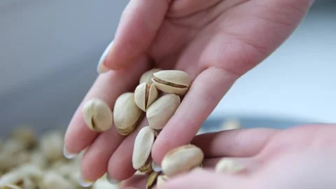 Slow motion man take roasted salted pistachios from white bowl on black paper Stock Footage 302104818