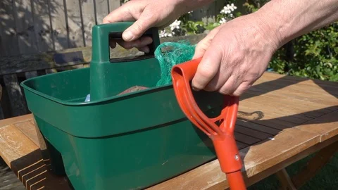 Slow motion: Man throwing gardening implements into a plastic container. Video stock 89793418