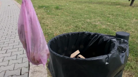 Slow motion: Man throws dog poop in the waste bin during a walk in nature Stock Footage 132940455