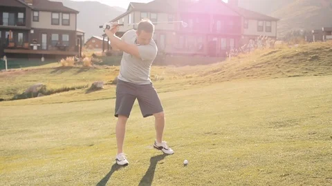 Slow motion of man using driver to hit ball on golf course with sunset Stock Footage 102674580