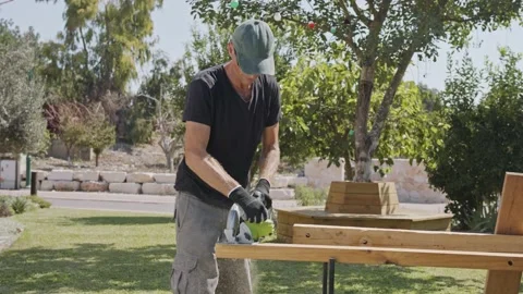 Slow motion of a man using a round saw to cut through wood Video stock 139576344