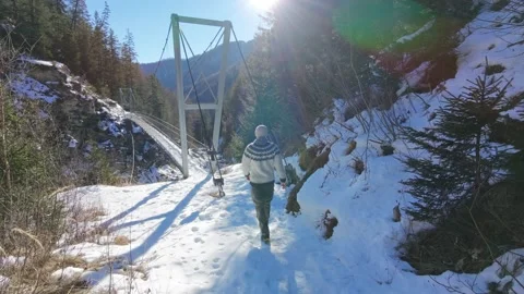 Slow motion man Walking Across Suspension Bridge Over River in Snowy Alps Stock Footage 326180510