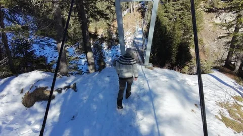 Slow motion man Walking Across Suspension Bridge Over River in Snowy Alps Stock-Footage 326180687