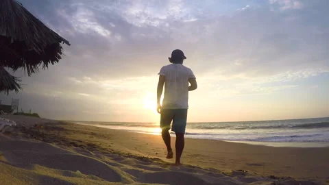 Slow motion man walking barefoot on the beach at golden sunset. Stock Footage 232177426