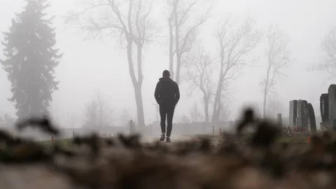 Slow Motion of Man Walking in Graveyard in Fog. Eerie Scenery on Cold Stock Footage 148070662